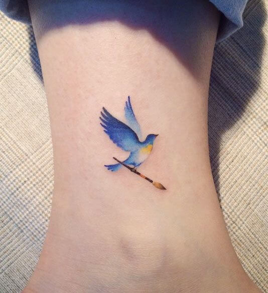 Watercolor style bluebird tattoo on the forearm